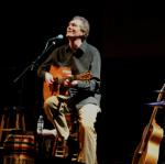 photo of Dennis Warner singing and playing guitar in concert