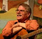 photo of Gordon Bok smiling and seated with his guitar on his lap