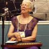 photo of Sally Campbell in concert, singing and strumming an autoharp.